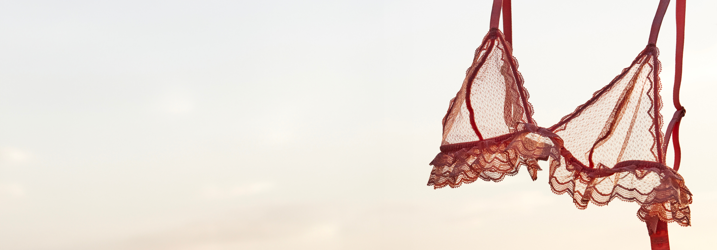 Une brassière en dentelle rouge orangé avec en fond le ciel
